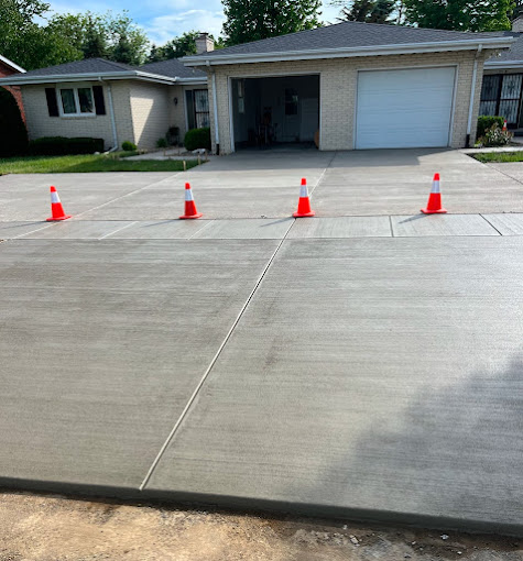 A driveway with orange cones on it and a house in the background